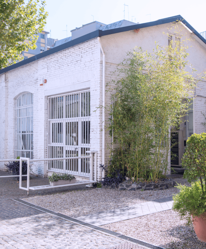 The exterior of one of the company's office buildings, featuring white bricks and a courtyard with plants.