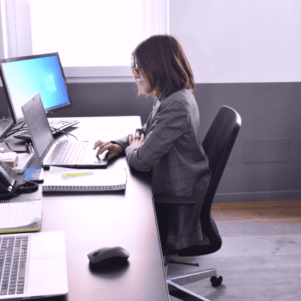 A team member working at a desk with multiple monitors and a laptop