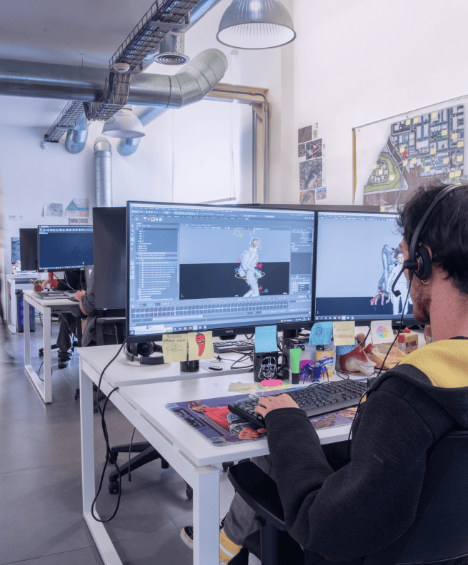 A team member working on 3D animation software at a desk in a modern office space.